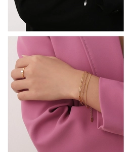 Detail of layered gold bracelet set and single diamond ring on female model in pink suit