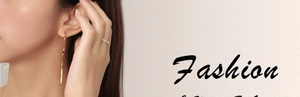 Detail of elegant gold wavy earrings and slim sparkling ring on a female model
