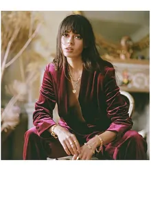 Close-up of gold chain bracelets and layered necklace with a round coin pendant on a model