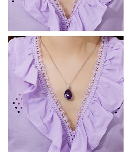 Macro detail of teardrop purple crystal pendant on silver titanium steel chain