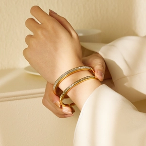 Detalle de brazaletes de acero dorado con cristales blancos de corte baguette