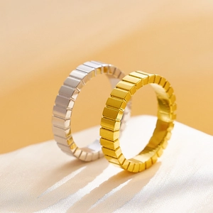 Detalle macro de anillos geométricos de oro y plata sobre seda blanca texturizada