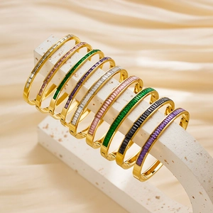 Primer plano de brazaletes de acero dorado con circonitas de colores en soportes blancos