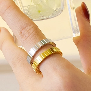 Primer plano de anillos minimalistas de acero de titanio en oro y plata con textura