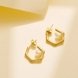 Detail of 18k gold plated hexagonal bamboo earrings with white round pearl inlays