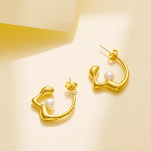 Detail of 18k gold plated stainless steel C-shape hoop earrings with inset pearl