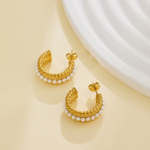 Detailed macro view of 18k gold-plated twisted hoop earrings with white pearl accents