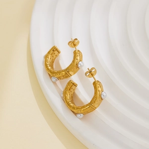 Macro detail of 18k gold stainless steel C-shaped earrings with pearls and hammered texture