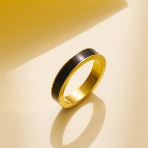 Dettaglio macro di anello minimalista in acciaio dorato con intarsio in smalto nero