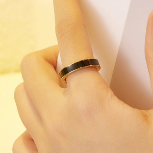 Dettaglio di un anello in acciaio inossidabile dorato con smalto nero sul dito