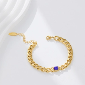 Detail of 18k gold plated Cuban chain bracelet with a faceted deep blue gemstone