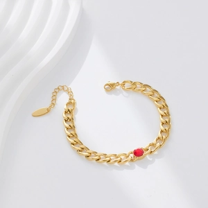 Detailed macro view of gold-plated Cuban chain bracelet with a red round zircon stone