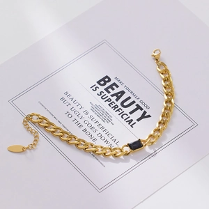 Macro detail of gold Cuban link bracelet featuring a rectangular black zircon center stone