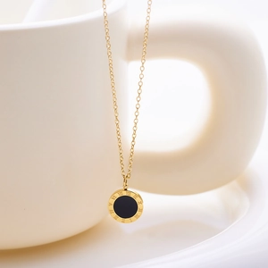 Close-up of golden disk pendant with black enamel center and Roman numeral engravings