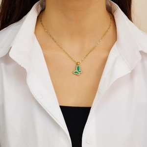 Detail of a gold butterfly necklace with green textured inlay and sparkling crystals