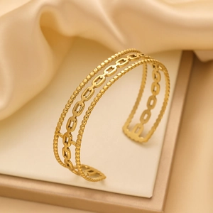 Détail d'un bracelet jonc doré en C avec motif à trois rangées de perles et maillons