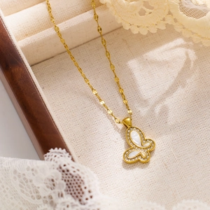 Close-up of golden butterfly pendant with shell inlay and crystal detail on lace