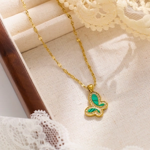 Macro shot of gold butterfly pendant with green malachite texture and crystal border