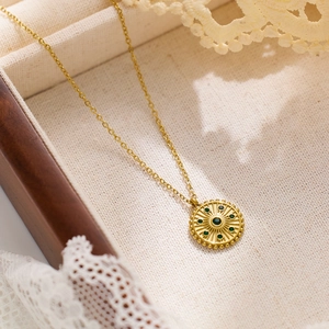 Gros plan détaillé d'un collier doré avec un pendentif radiant orné d'un zircon vert