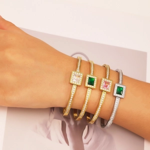 Detailed view of four emerald and zircon studded luxury stainless steel bangles on a wrist