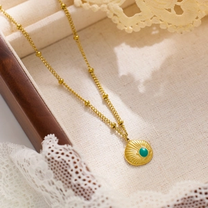 Detail of vintage gold satellite chain with a sunburst round pendant and green stone