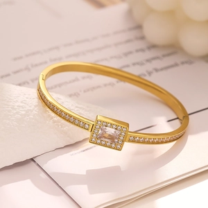 Detail of gold-tone bangle featuring a square zircon pendant with pavé diamond accents