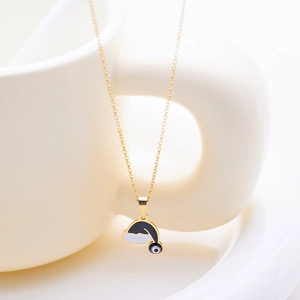 Detailed macro view of a gold-plated necklace featuring a Christmas hat and evil eye charm