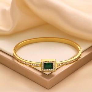 Detailed macro of vintage gold bangle with emerald zirconia and micro-set diamonds