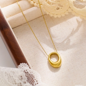 Gros plan détaillé du pendentif ovale en or poli sur fond de dentelle et de bois décor