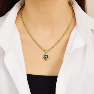 Close-up of heart-shaped green enamel necklace with a gold rope chain on a model