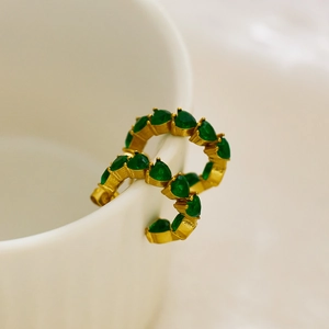 Detail of C-shaped gold-plated twist hoop earrings with emerald heart-cut crystals