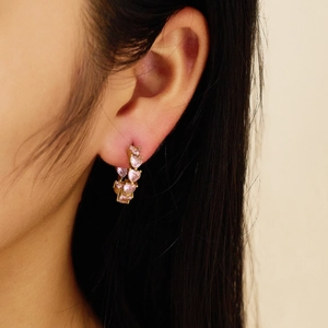 Detailed close-up of a pink heart gemstone hoop earring worn on a model's ear