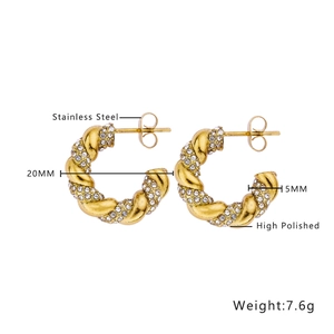 Detailed view of high polished 20mm gold twist earrings with emerald and clear zircon