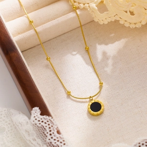 Golden necklace with round Roman numeral pendant and black inlay on wooden jewelry box