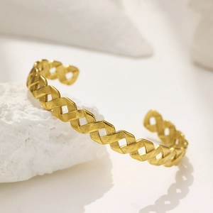 Vue détaillée du bracelet jonc doré en forme de C avec motifs croisés texturés