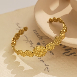 Détail du bracelet jonc plaqué or 18 carats avec texture martelée sur papier vintage