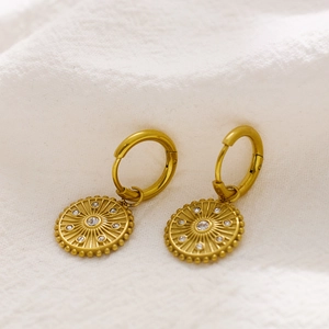 Detailed close-up of gold titanium hoop earrings with sunburst charms and zircon inlays