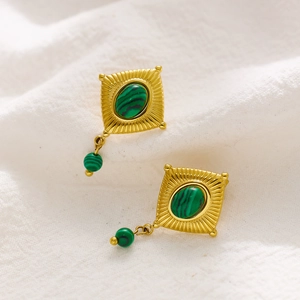 Macro detail of gold vintage earrings with malachite stones on white linen background