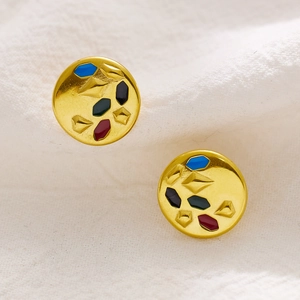 Macro detail of vintage gold hoop earrings with colorful enamel geometric patterns