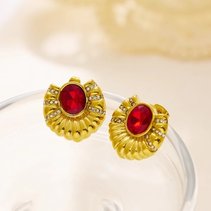 Detailed macro view of vintage gold earrings with red oval gemstone and white rhinestones