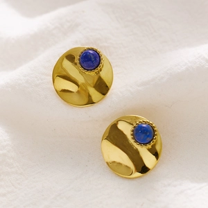 Detail of vintage golden earrings with lapis lazuli stone and hammered metal texture