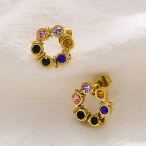 Macro view of gold hoop earrings set with colorful multi-tone faceted gemstones