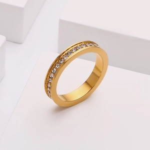 Dettaglio macro dell'anello dorato con cristalli incastonati su base minimalista