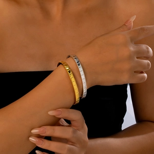 Détail de bracelets en acier inoxydable doré et argenté avec textures à facettes au poignet
