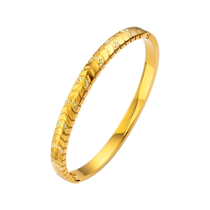 Vista detallada del brazalete de acero dorado con diseño de flecha e incrustación de circón