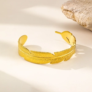 Dettaglio del bracciale a polsino in oro piuma con trama intricata e finitura metallica