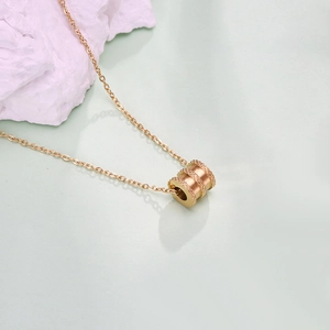 Macro-opname van gouden cilindrische hanger met kartelpatroon en fijne O-ketting