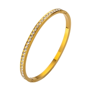 Vista detallada de un brazalete fino de acero dorado con circonitas blancas