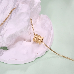 Macro-opname van de gouden cilinderhanger met ruitpatroon aan een fijne ketting
