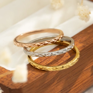 Detailweergave van stapelbare titaniumstalen ringen met diamantgeslepen textuur in drie kleuren